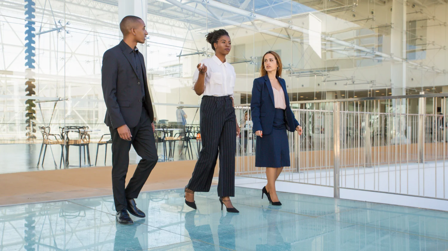 Três executivos caminham em lobby corporativo moderno